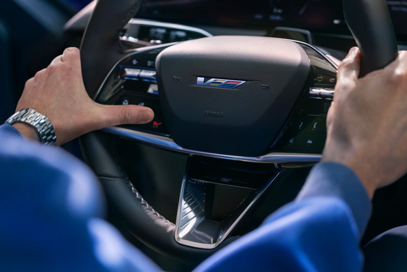 Close-up of a Man About to Press the V-Button on the 2026 OPTIQ-V Steering Wheel | Bergstrom Cadillac of Oshkosh in Oshkosh WI