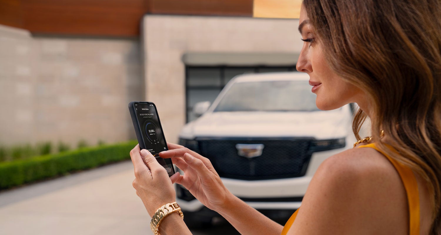 lady checking her mobile with a Cadillac vehicle background | Bergstrom Cadillac of Oshkosh in Oshkosh WI